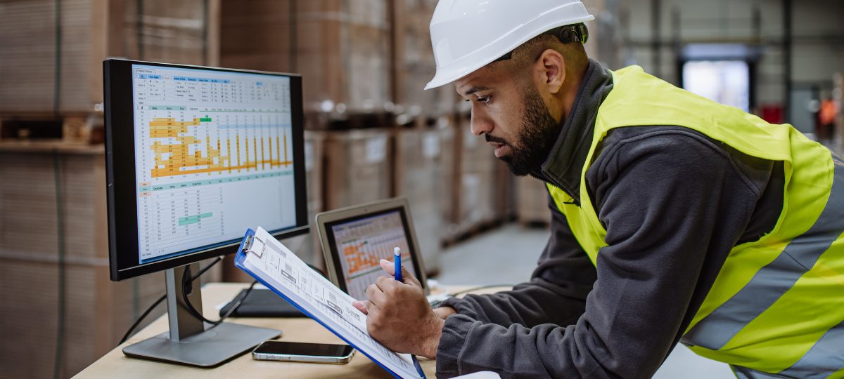 Profesional con casco revisando información en bodega
